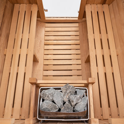 Redwood Outdoors 6 person Barrel Outdoor Sauna made of hemlock, inside view from above, two benches on either side with a heater in the rear.