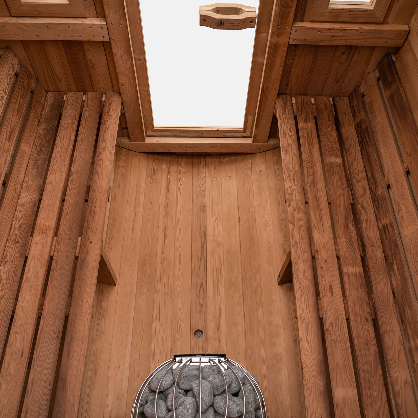 Redwood Outdoors 6 person Barrel Outdoor Sauna made of hemlock, inside view from above, two benches on either side with a heater in the rear.