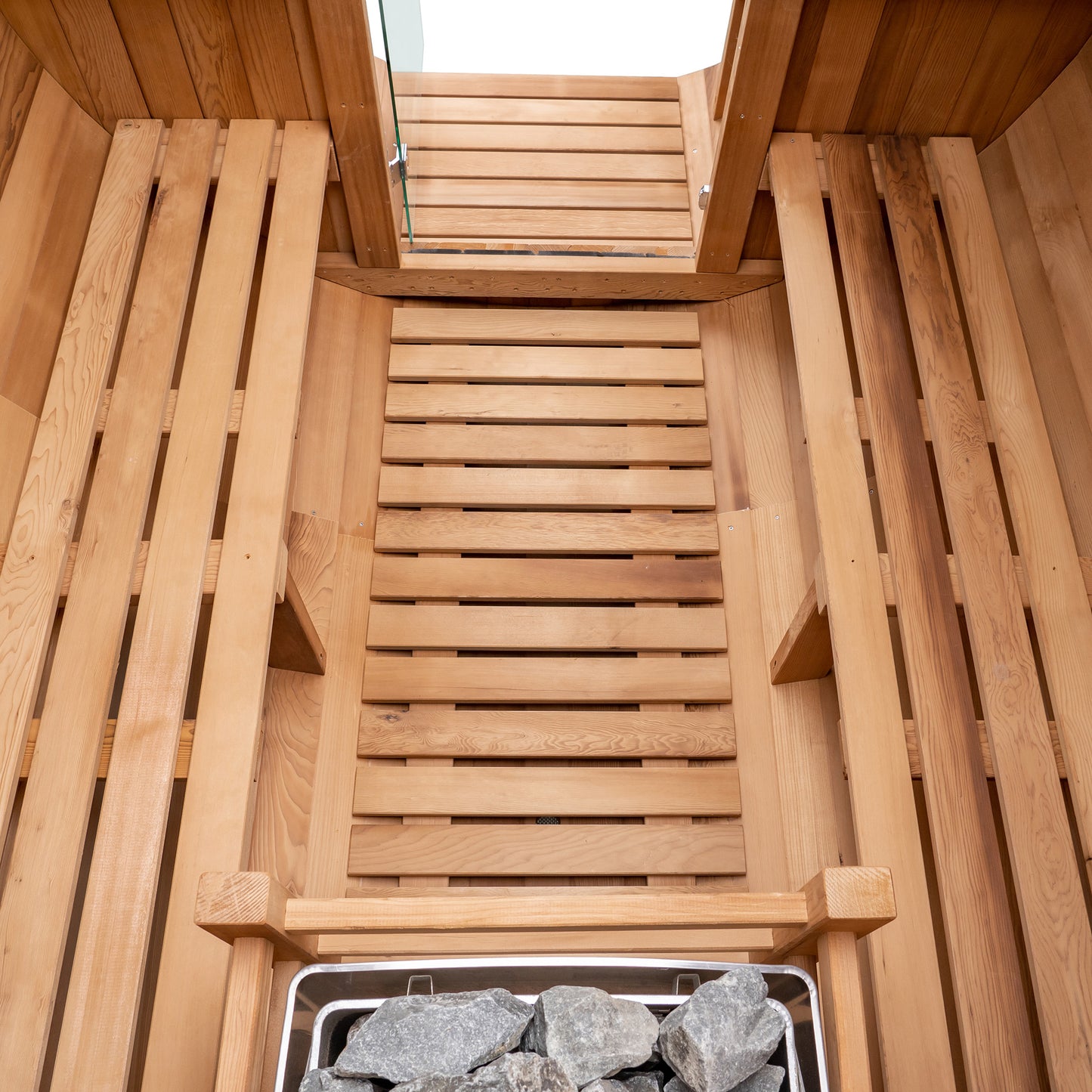 Redwood Outdoors 6 person Barrel Outdoor Sauna made of hemlock, inside view from above, two benches on either side with a heater in the rear.