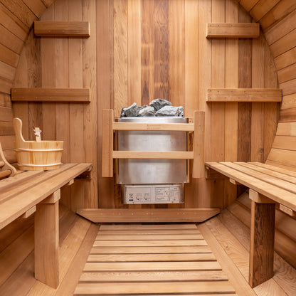 Redwood Outdoors 6 person Barrel Outdoor Sauna with porch made of hemlock, inside view from the front, two benches on either side with a heater in the rear.
