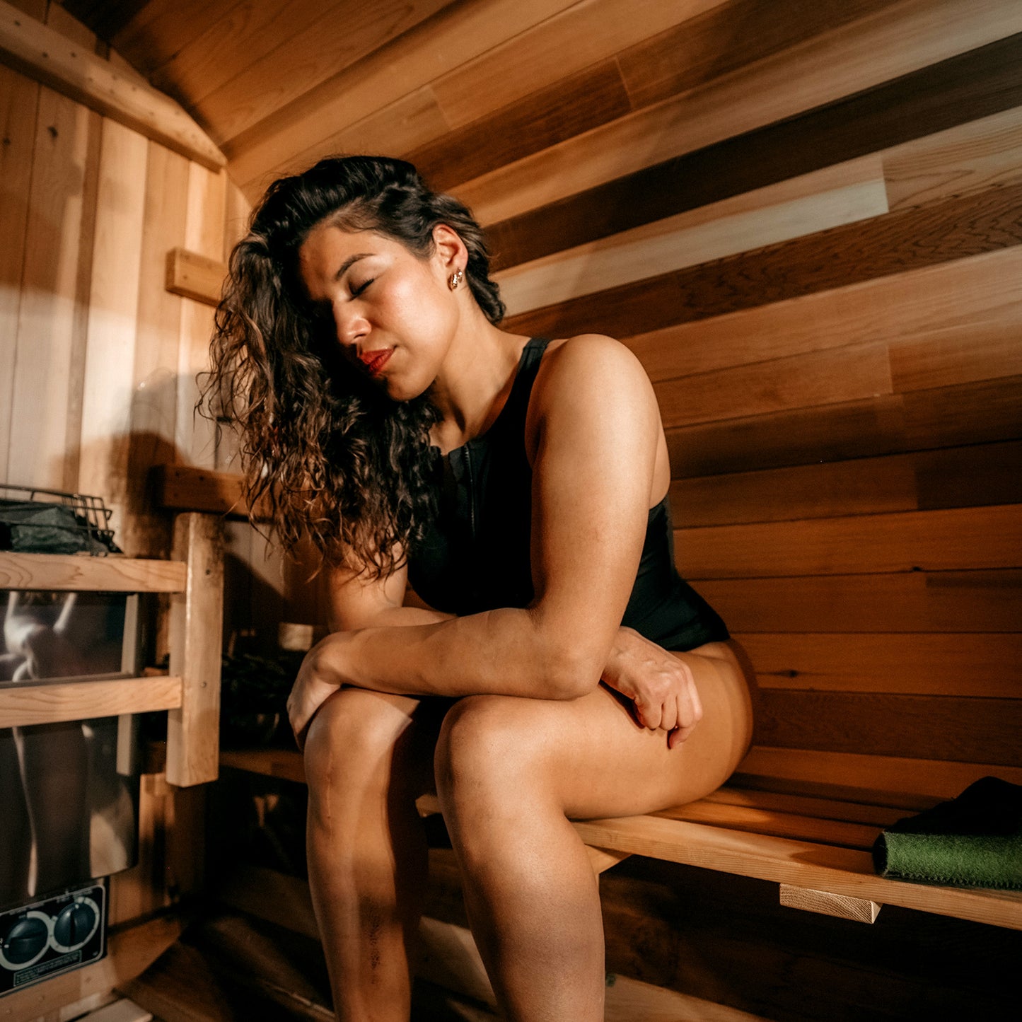 Redwood Outdoors 6 person Barrel Outdoor Sauna with porch made of hemlock, inside view of one person sitting inside the sauna. 