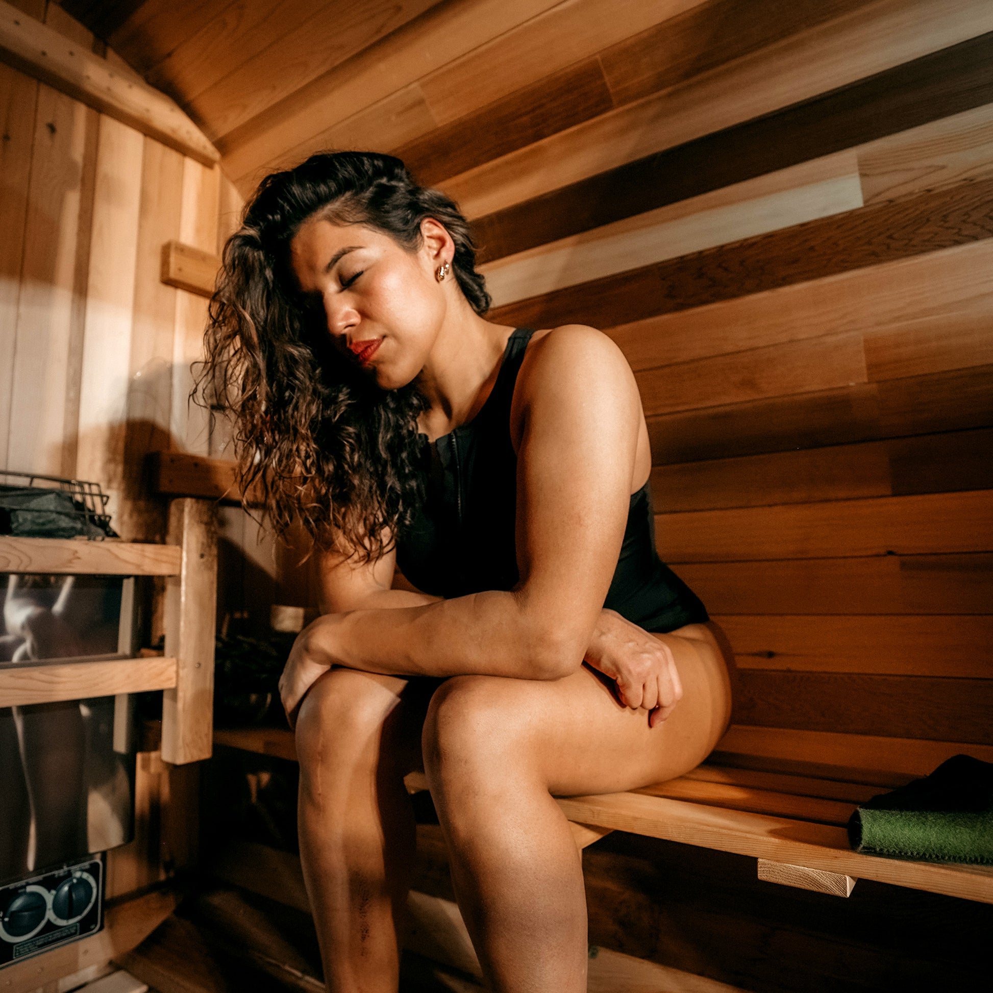 Redwood Outdoors 6 person Barrel Outdoor Sauna with porch made of hemlock, inside view of one person sitting inside the sauna. 