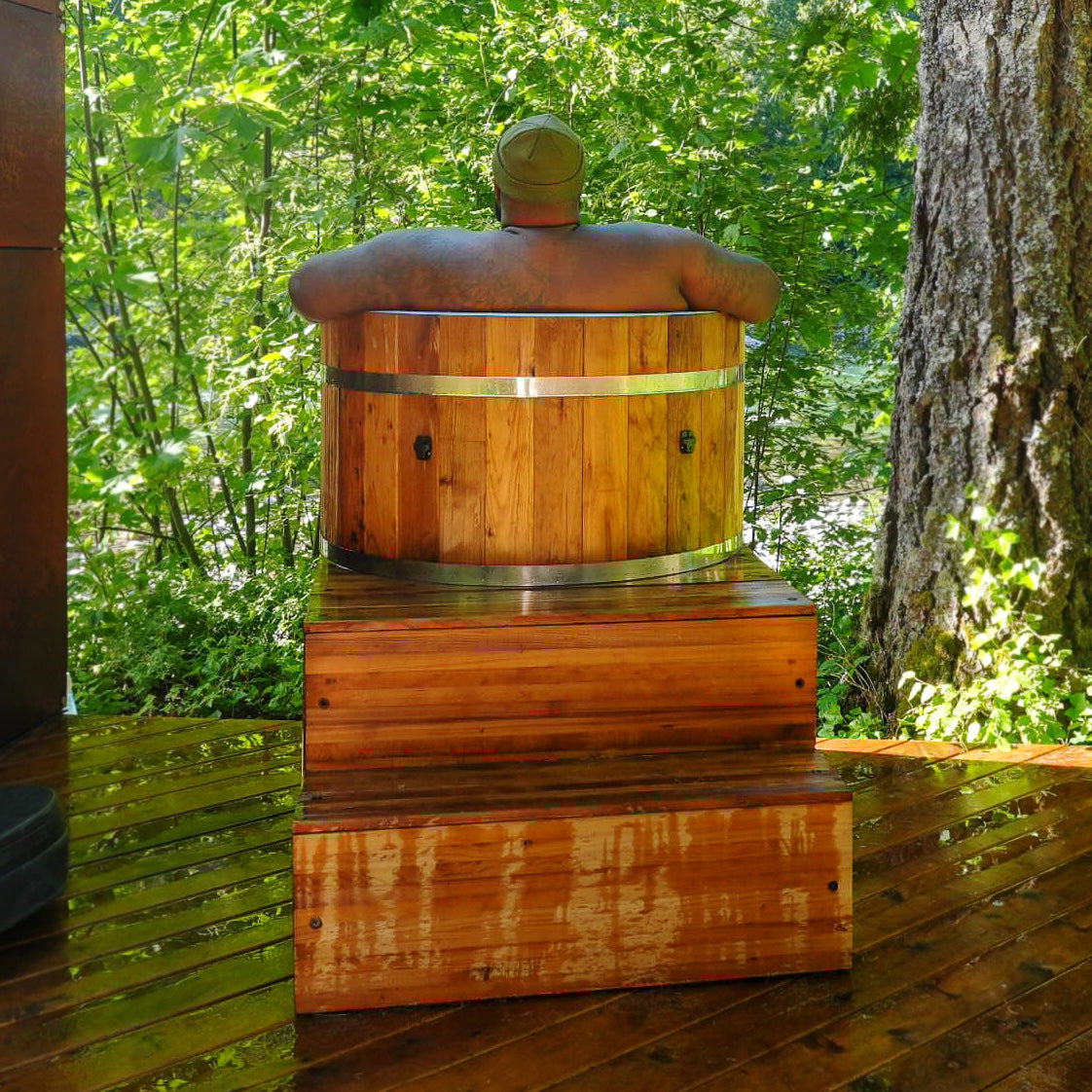 Redwood Outdoors Alaskan All-In_One Cold Plunge Tub made of heat treated wood exterior lifestyle view with a person in the tub.