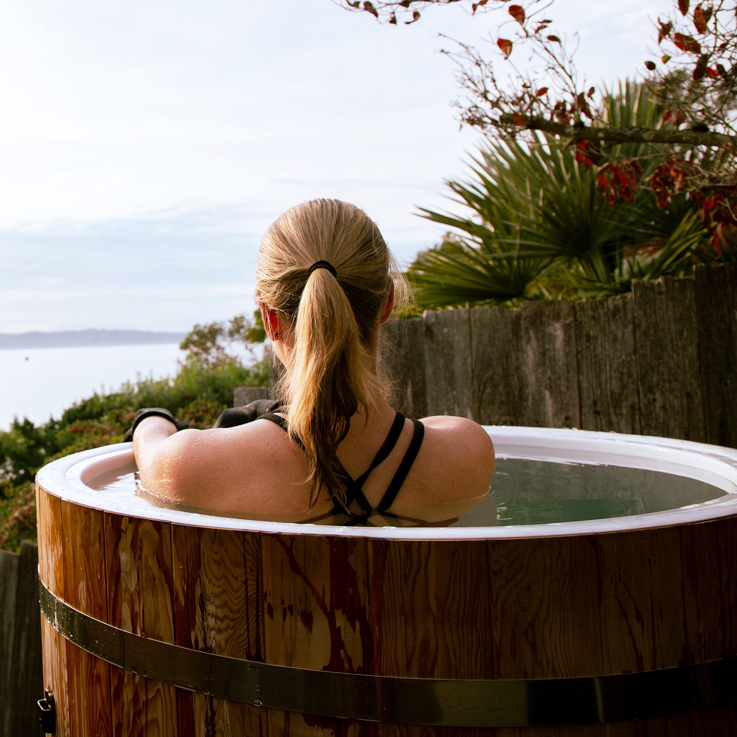 Redwood Outdoors Alaskan All-In_One Cold Plunge Tub made of heat treated wood exterior lifestyle view with a person in the tub with water. 