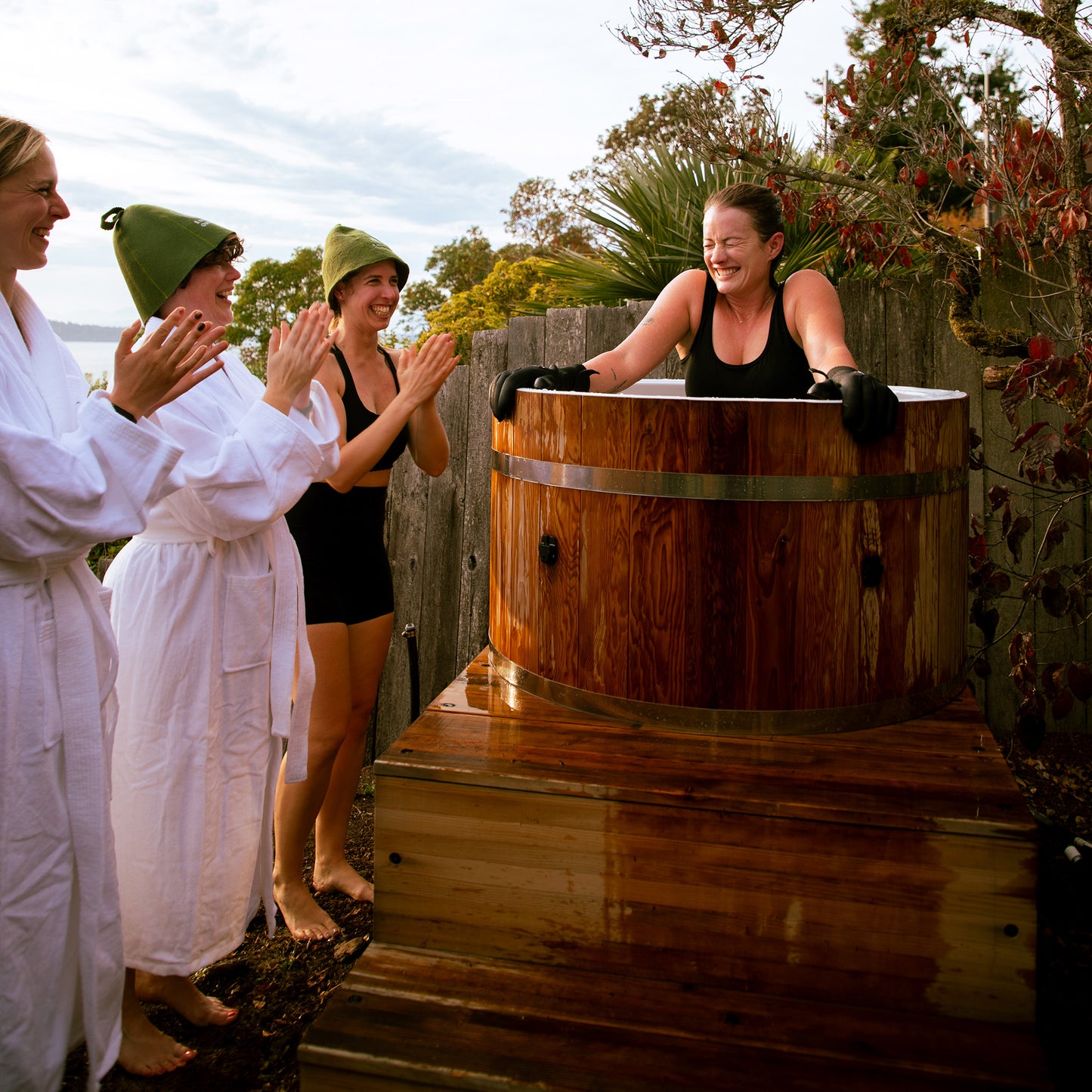 Redwood Outdoors Alaskan All-In_One Cold Plunge Tub made of heat treated wood exterior lifestyle view with a person in the tub with three other people outside of the tub.