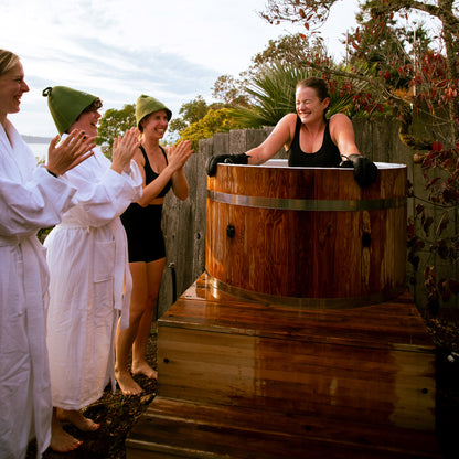 Redwood Outdoors Alaskan All-In_One Cold Plunge Tub made of heat treated wood exterior lifestyle view with a person in the tub with three other people outside of the tub.