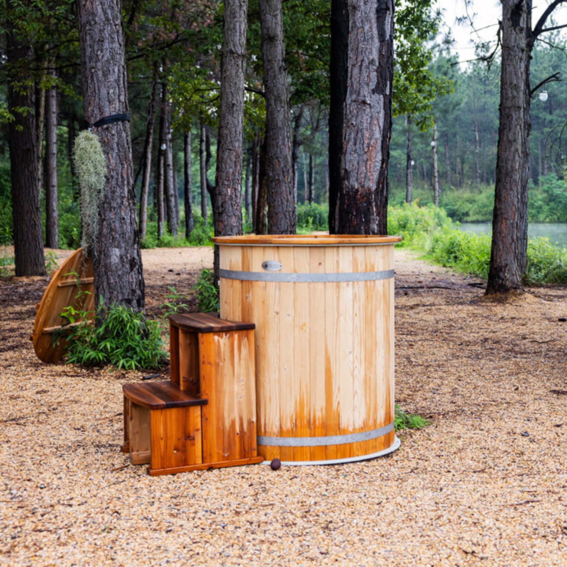 Redwood Outdoors Alaskan Cold Plunge Tub made of heat treated wood exterior view with the lid off and stairs in a forested area.