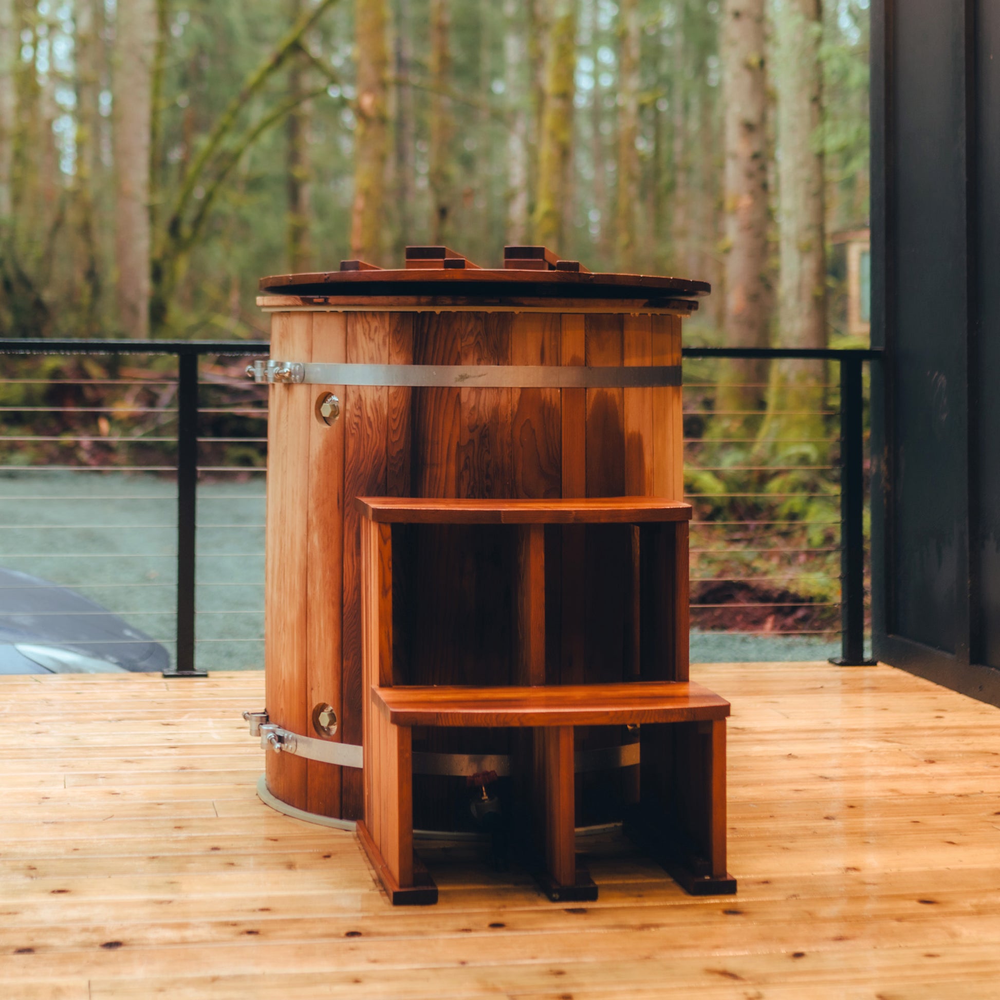 Redwood Outdoors Alaskan Cold Plunge Tub made of heat treated wood exterior view with the lid on and stairs placed on a porch.