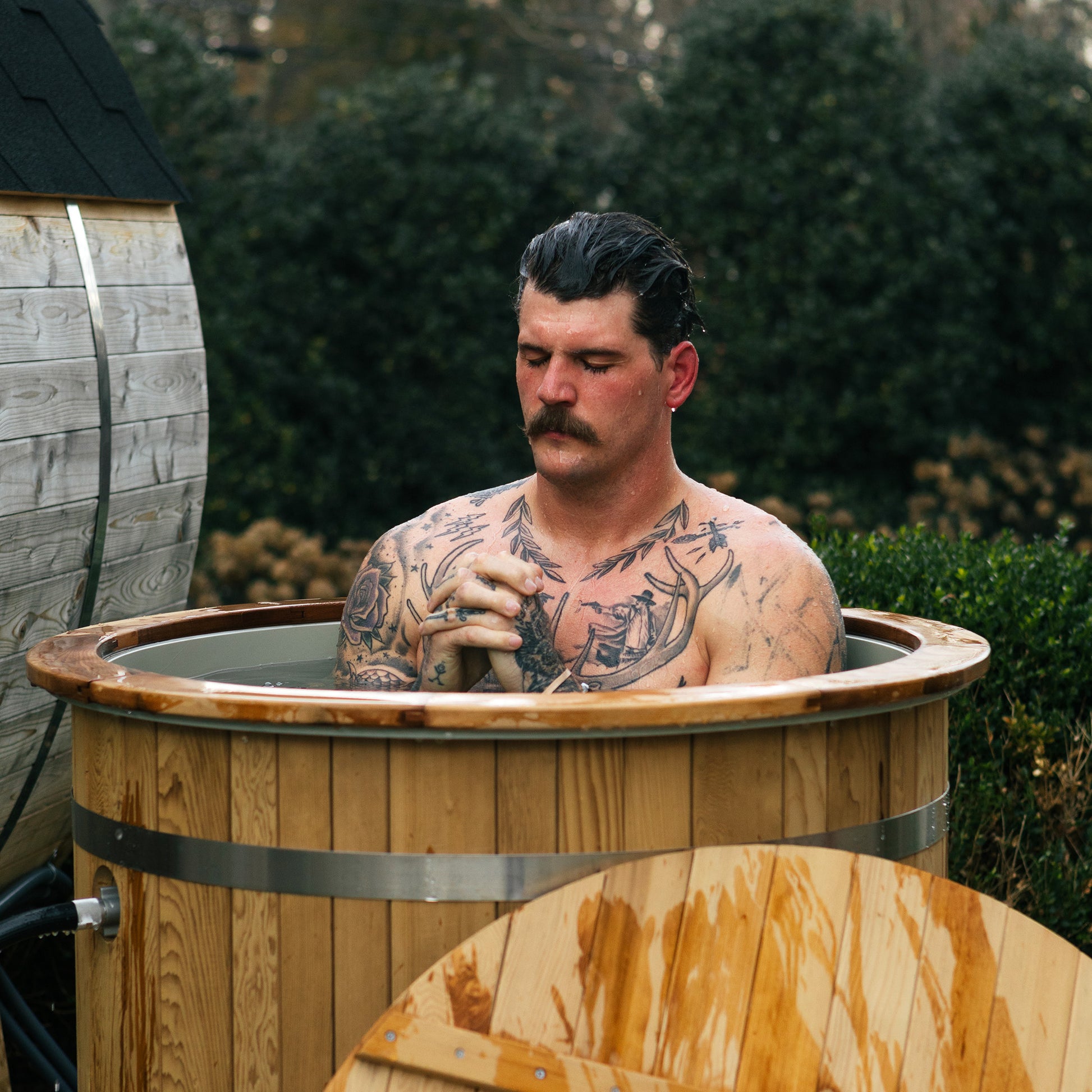 Redwood Outdoors Alaskan Cold Plunge Tub made of heat treated wood exterior with a person in the tub with water.