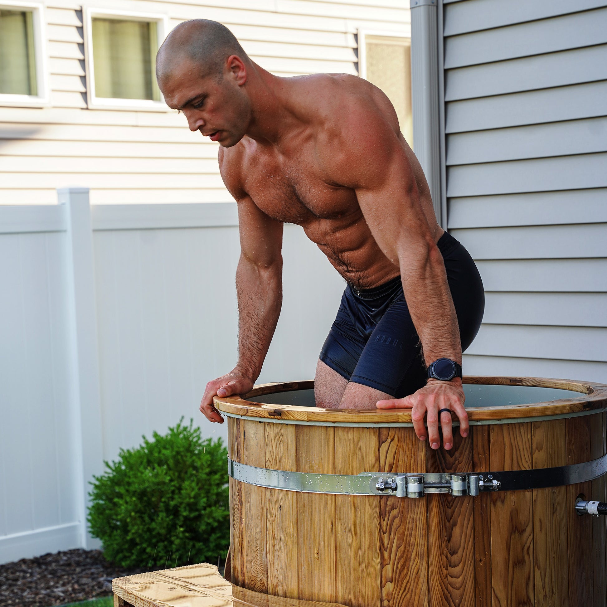 Redwood Outdoors Alaskan Cold Plunge Tub made of heat treated wood exterior with a person entering the tub with water.