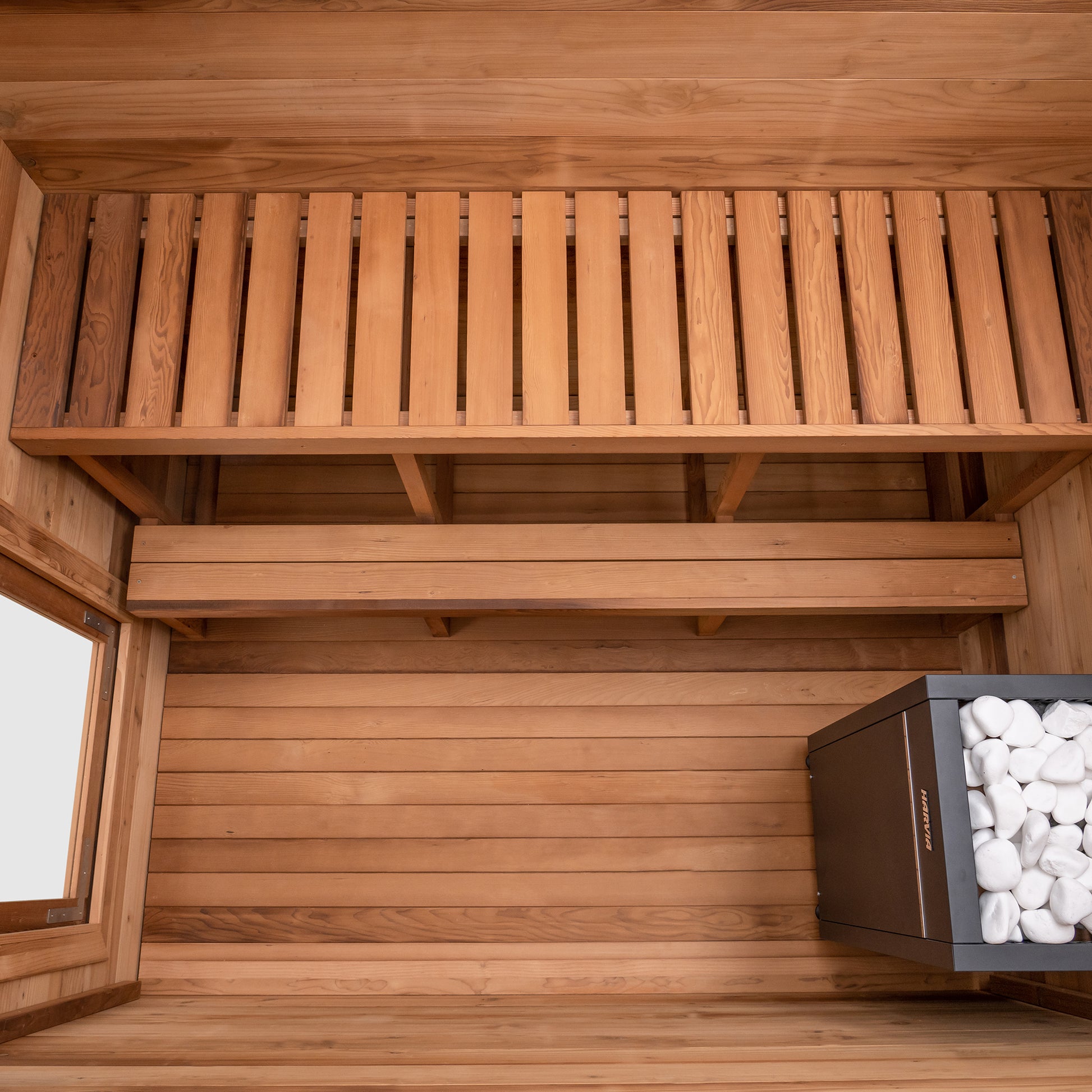 Redwood Outdoors Cove 3 person sauna made of Hemlock wood. A above view of the inside of the sauna with the wooden bench, foot rest and a heater in the corner.