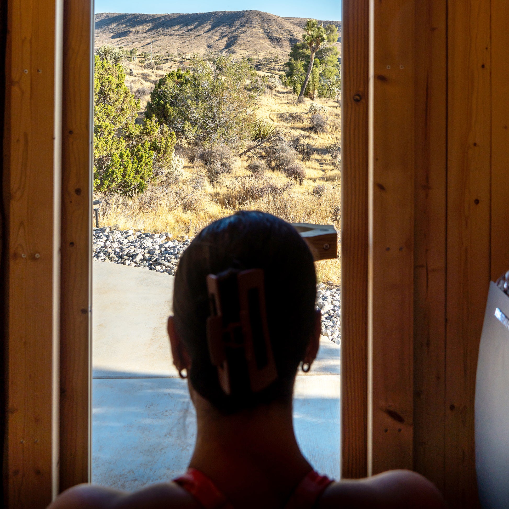 Redwood Outdoors Duo 2 person outdoor sauna, made of hemlock wood with a glass door indoor view with a person looking outside of the full glass door 