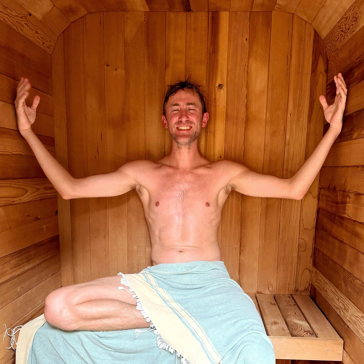 Redwood Outdoors Duo 2 person outdoor sauna, made of hemlock wood an interior view of a person sitting on a sauna bench.