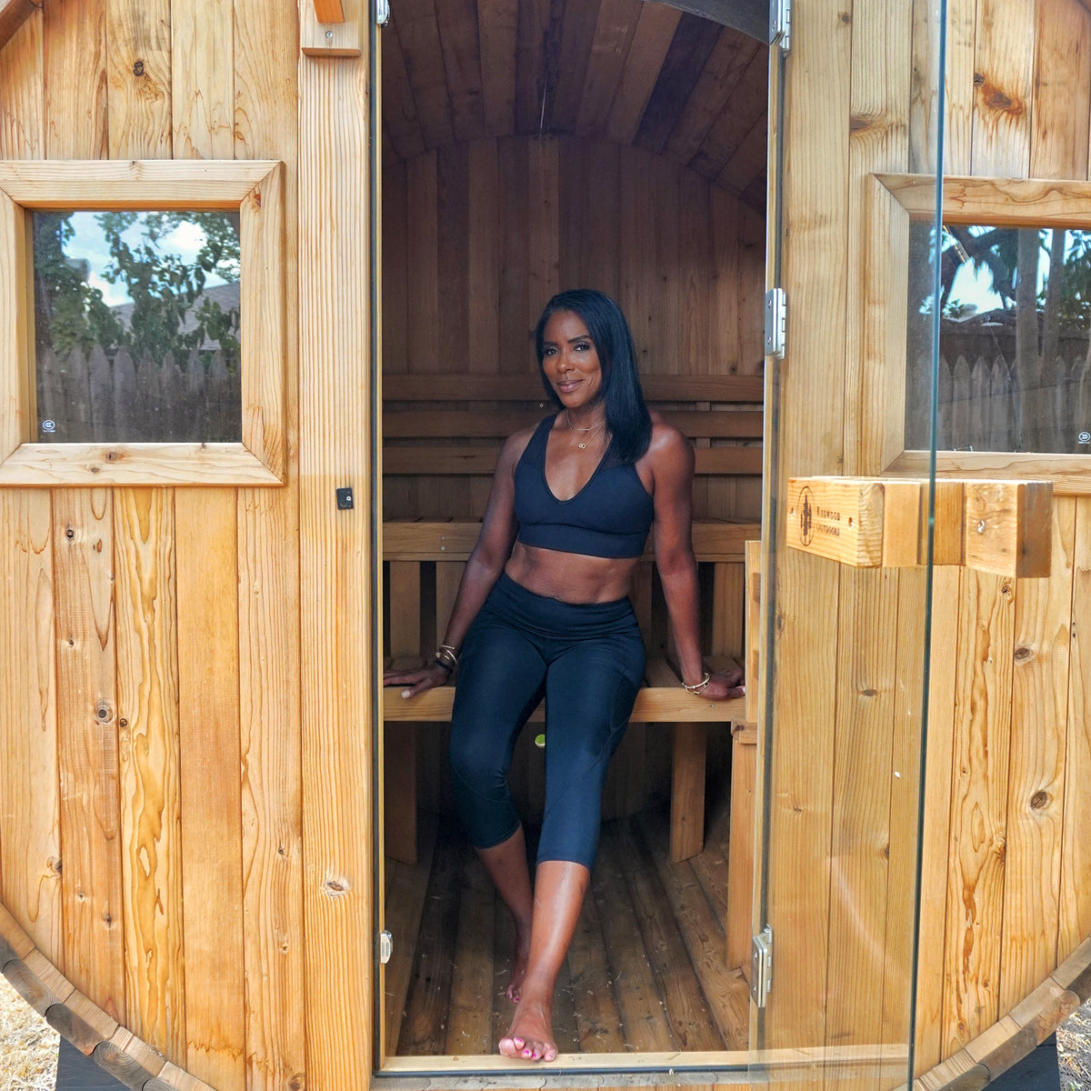 Redwood Outdoors Extra Wide 6 person Barrel Outdoor Sauna life style view of a person sitting on the lower bench of the sauna. 