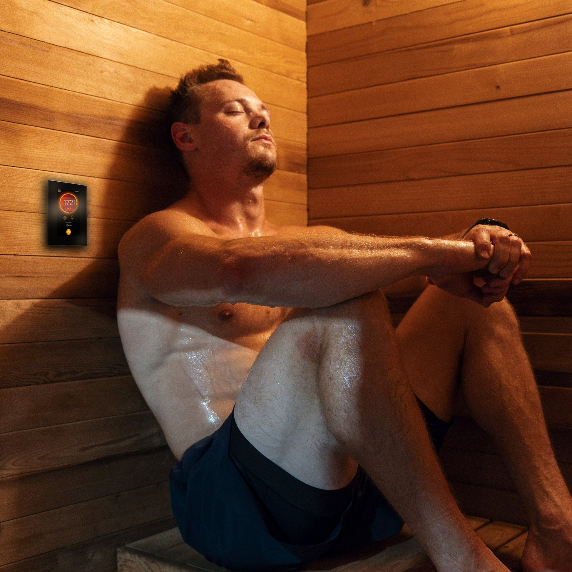 Harvia Fenix WiFi heater controller shown installed in a sauna next to a person.