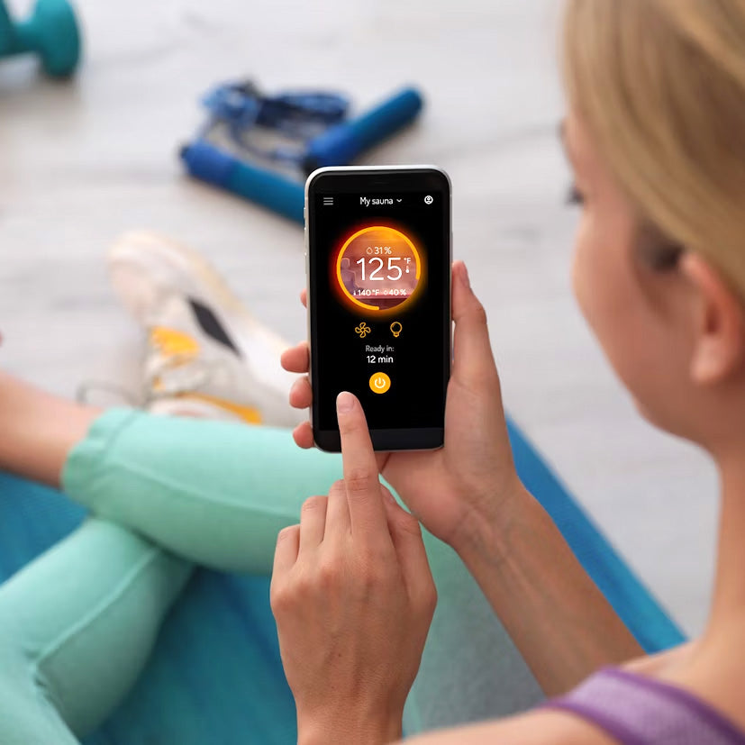 View of the MyHarvia 2 app being shown on a smart phone displaying the saunas temperature while a person is in a gym.