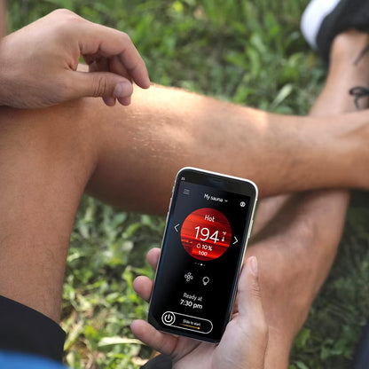 View of the MyHarvia 2 app being shown on a smart phone displaying the saunas temperature while a person is outside.