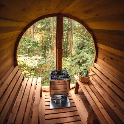  Redwood Outdoors Horizon 6 person outdoor sauna made of Hemlock wood. A front view of the inside of the sauna with a wooden bench on either side and a large glass covering the back wall with a woods in the background. 