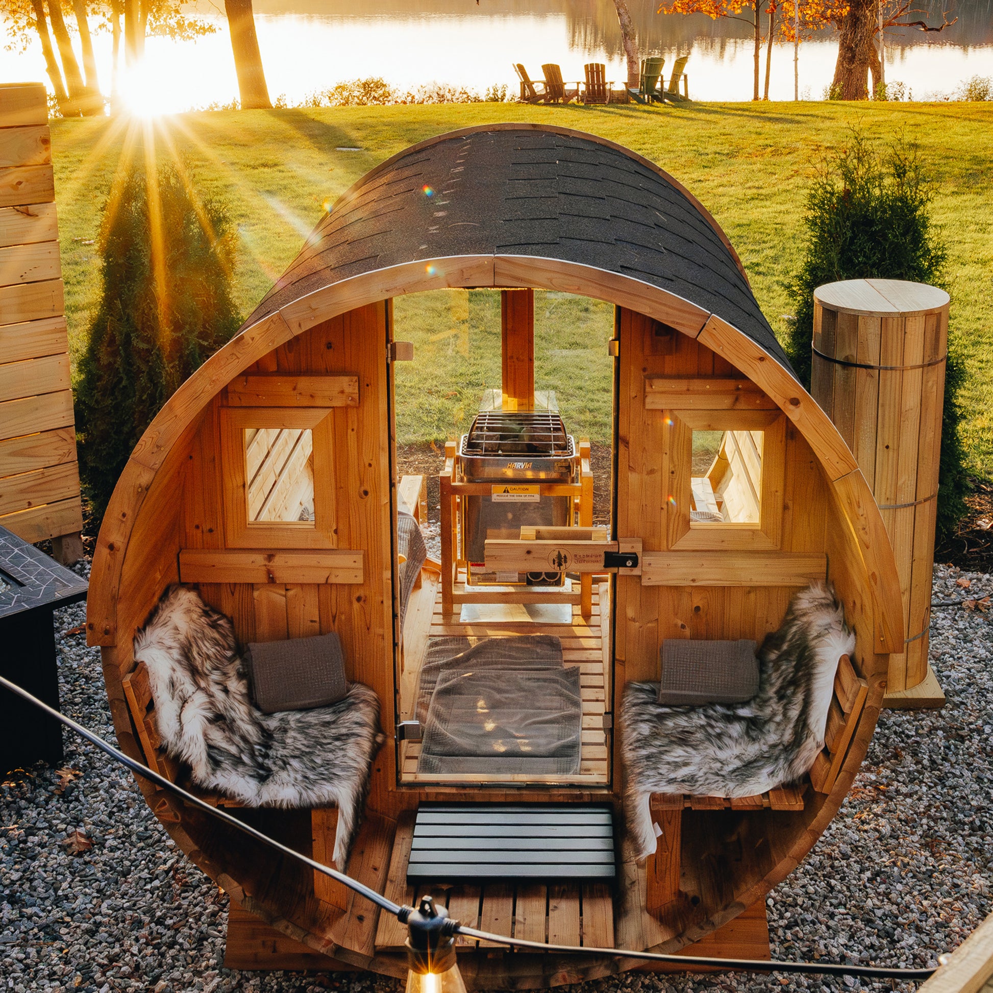 Redwood Outdoors Horizon 6 person outdoor sauna with porch front view of sauna in a backyard with a lake in the background during the daylight. 