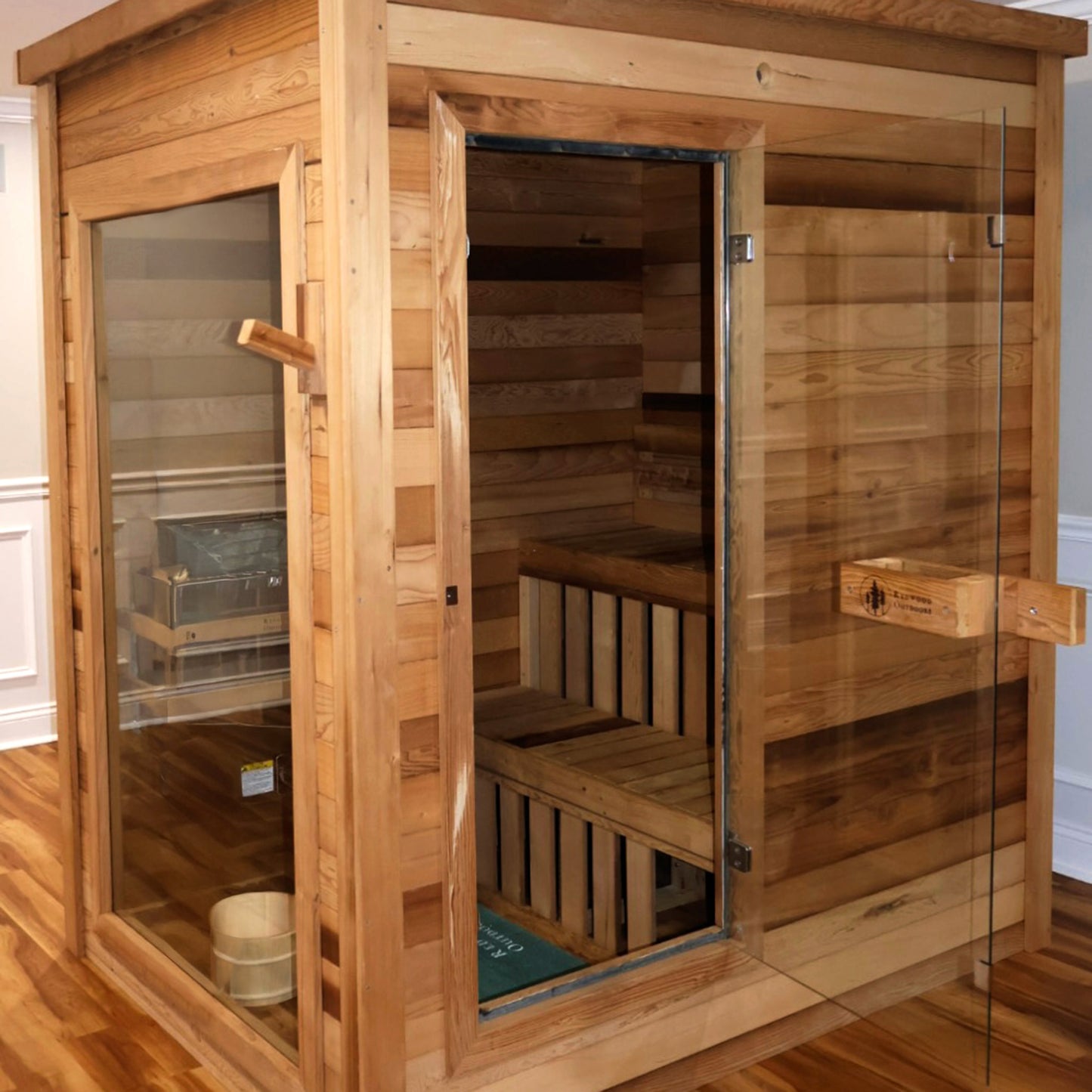 Redwood Outdoors Retreat 4 person indoor sauna, made of hemlock wood with a glass door and window exterior front view in a home