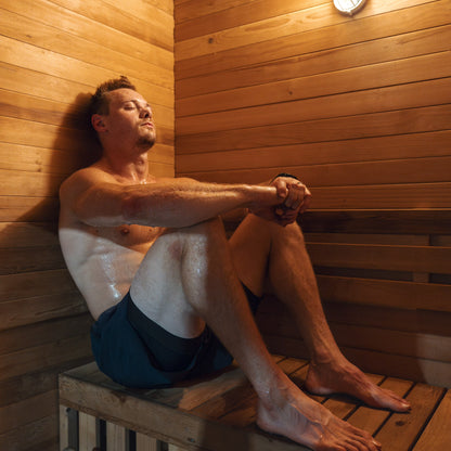 Redwood Outdoors Sanctuary 4 person indoor sauna, made of hemlock wood view of a person sitting in the sauna on the bench