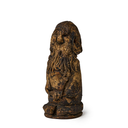 Small figure of an elf covered in pine tar side view