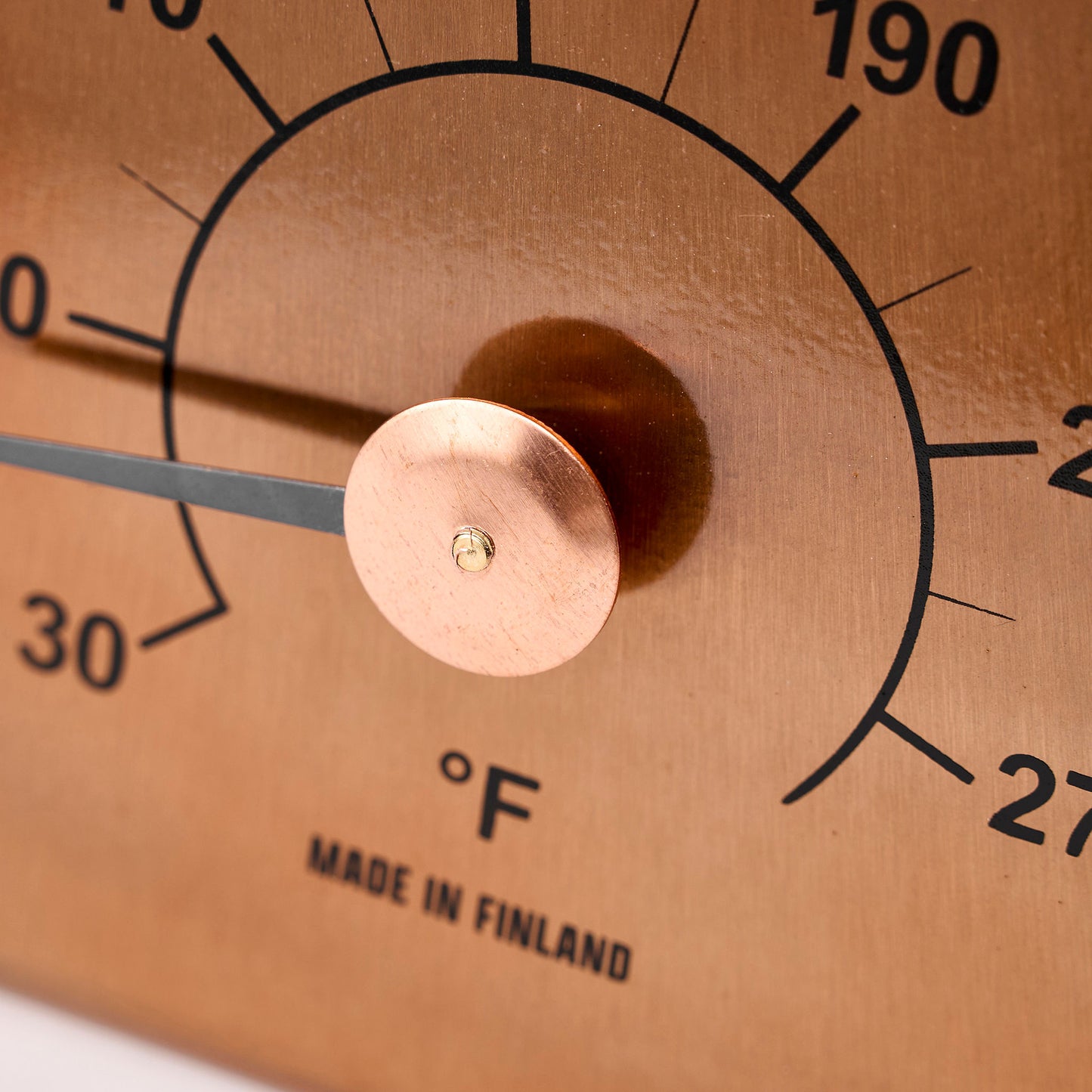 Copper thermometer with temperature markings close up of dial view.