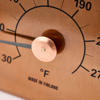 Copper thermometer with temperature markings close up of dial view.