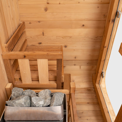 Redwood Outdoors Solo 1 person outdoor sauna, made of hemlock wood with a glass door interior view of bench and heater from the side.