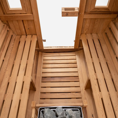 Redwood Outdoors Vista 6 person outdoor sauna, made of hemlock wood with large rear window, heater with guard and two benches on both sides. 